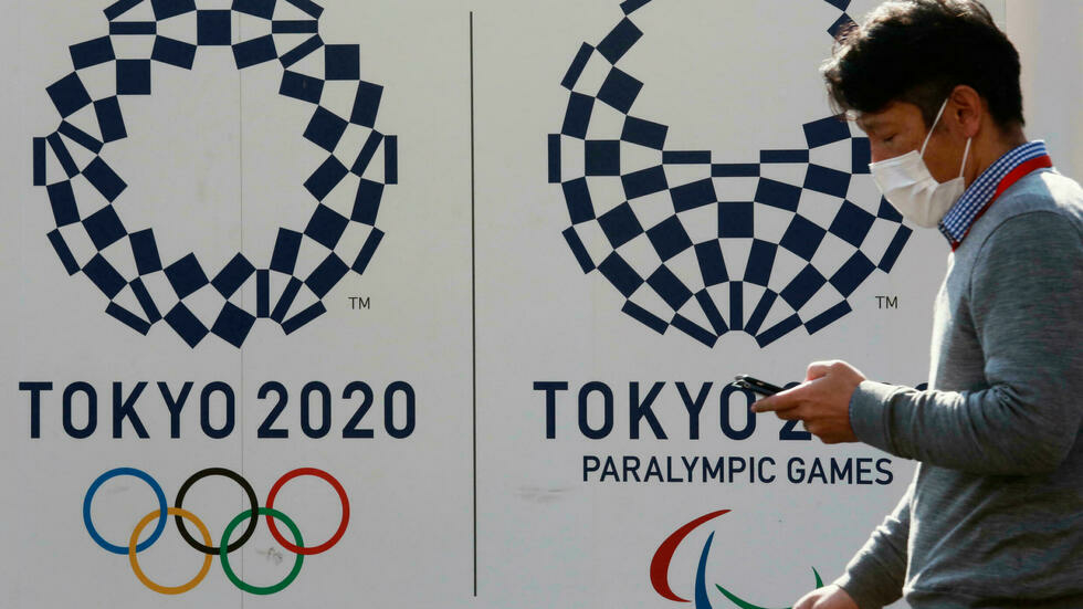 A man walks by logos of the Tokyo Olympic and Paralympic Games in Tokyo, Japan, February 1, 2021. © Koji Sasahara, AP