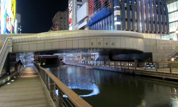 The pedestrian riverside area of ​​Ebisu Bridge crossing Dotonbori River in Chuo Ward of Osaka City.  Photo by Flickr/Wally Gobetz.