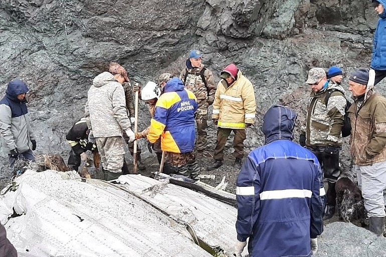 Specialists of the Russian Emergencies Ministry are seen at the crash site of a Russian An-26 passenger plane near the village of Palana in the north of the Kamchatka Peninsula, Russia, July 7, 2021 [Russia's Emergencies Ministry/Handout via Reuters]