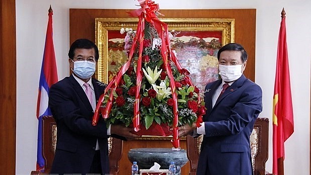 Deputy head of the Lao People’s Revolutionary Party Central Committee’s Commission for External Relations Somphone Sichaleun (L) presents flowers to Deputy Foreign Minister Phoxay Khaykhamphithoune (Photo: VNA)
