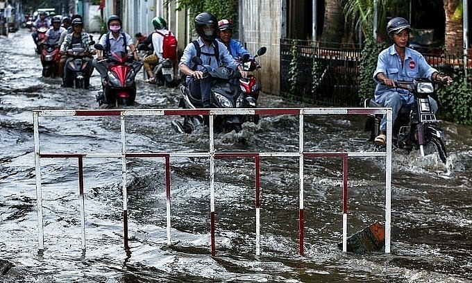 People drive through a flooded street due to high tides in District 2 of Ho Chi Minh City in October 2019. Photo by VnExpress