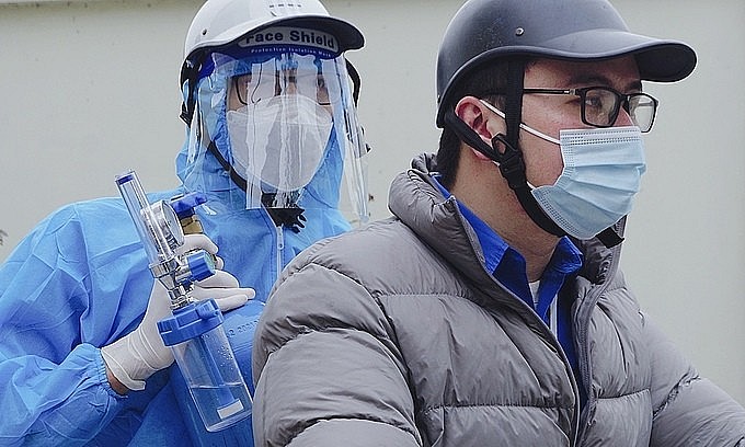 A health worker in Hanoi's Hoang Mai District brings an oxygen canister to the home of a Covid-19 case. Photo: VnExpress