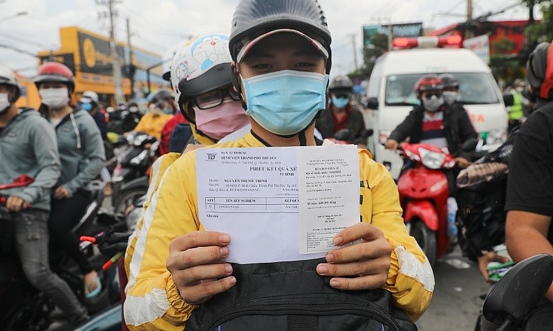 A motorbike driver holds up his Covid-19 test result in Ho Chi Minh City, Oct. 1, 2021. Photo by VnExpress