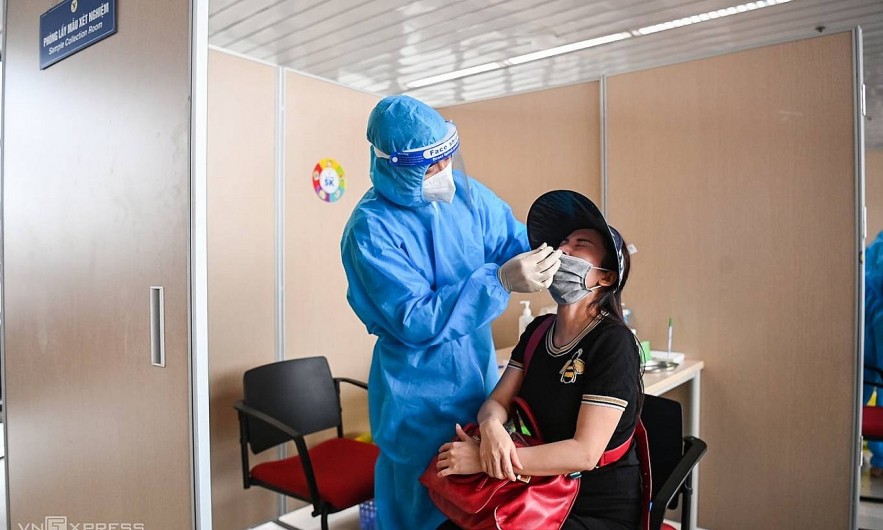 A health worker collects coronavirus test samples from a passenger at Hanoi's Noi Bai Airport. Photo by VnExpress