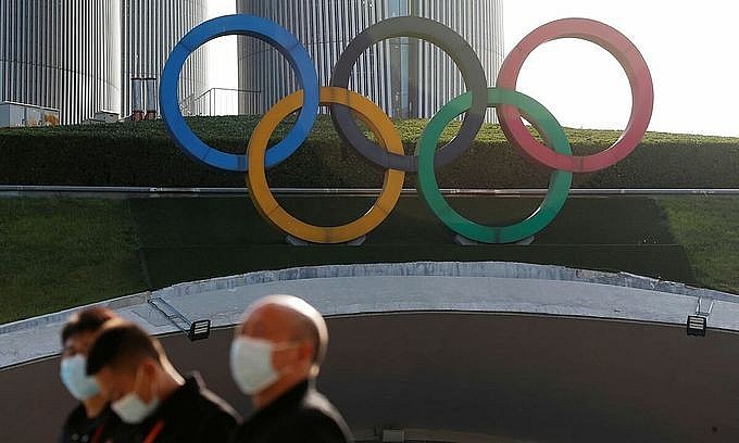 People wearing face masks following the coronavirus disease (Covid-19) outbreak stand near Olympic rings before the ceremony to welcome the Olympic flame for the Beijing 2022 Winter Olympics, in Beijing, China October 20, 2021. Photo: Reuters