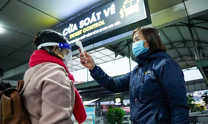 A staff checks temperature of a bus passenger at Nuoc Ngam Bus Station in Hanoi, December 31, 2021. Photo: VnExpress