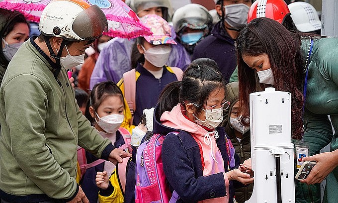 Hanoi first graders disinfect their hands and have their temperature checked before attending school for the first time, Feb. 10, 2022. Photo: VnExpress