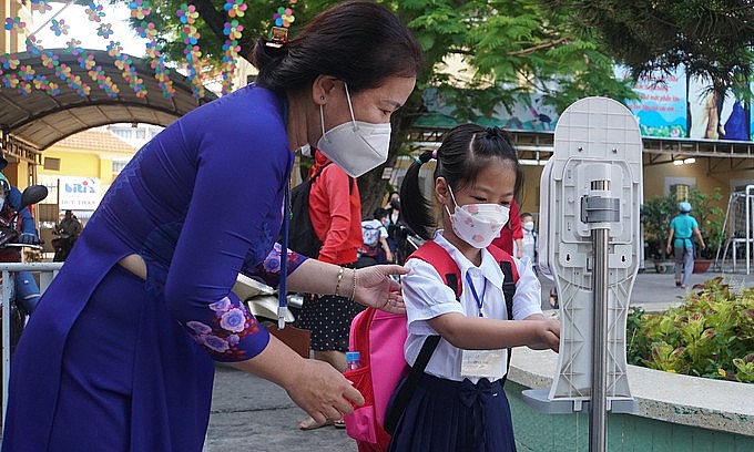 A teacher guides a student to disinfect her hands before entering class at an elementary school in HCMC's Binh Thanh District, February 14, 2021. Photo: VnExpress