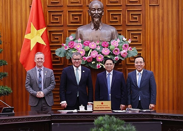 Prime Minister Pham Minh Chinh (second, right), British Cabinet Minister and COP26 President Alok Kumar Sharma (second, left), and other officials pose for a photo at the meeting in Hanoi on February 14. Photo: VNA