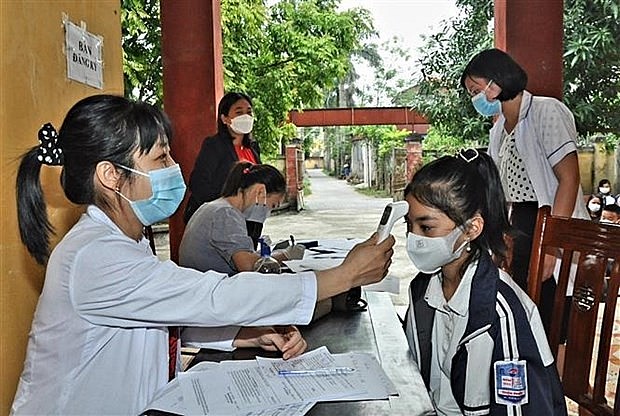 A student gets temperature check before receiving COVID-19 vaccination in Hung Yen province. Photo: VNA