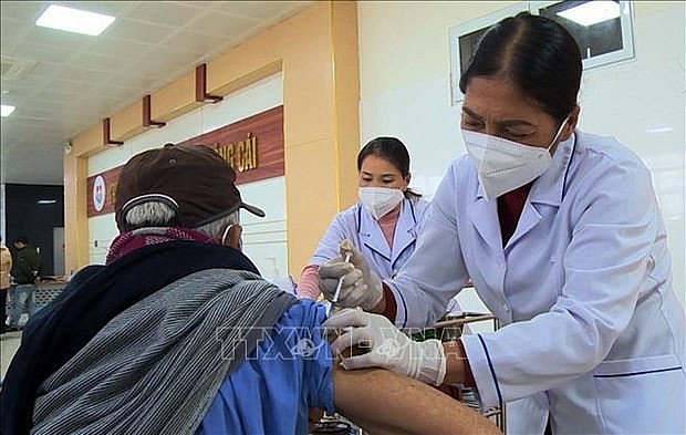 Health workers administer COVID-19 vaccine shot for a senior citizen. Photo: VNA