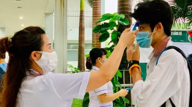 A student has his body temperature checked before entering the exam room. Photo: NDO