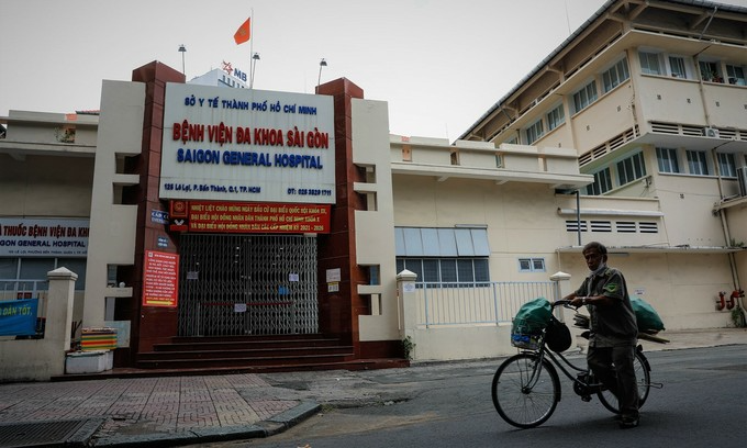 A man walks a bicycle past the Saigon General Hospital in HCMC's District, June 22, 2021. The hospital is currently locked down as linked to at least five Covid-19 cases. Photo: VnExpress