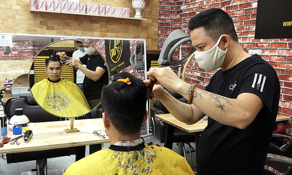 A customer has a haircut at a barbershop on Hanoi's Nguyen Hong Street on June 22, 2021. Photo: VnExpress