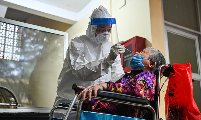 A medic takes the sample of a woman in Hanoi during a mass coronavirus test, May 2021. Photo by VnExpress/Giang Huy.