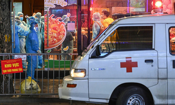 An ambulance and medical workers arrive at a pizza shop on Hanoi's Doan Tran Nghiep Street to lock it down due to Covid linkage, July 15, 2021. Photo: VnExpress