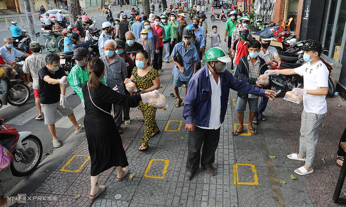 Poor people receive free meals from a restaurant in HCMC's District 1, June 2021. Photo: VnExpress