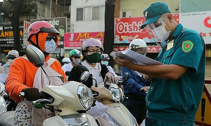 A man checks the approval documents of vehicles passing through a Covid-19 checkpoint on Nguyen Kiem Street in Go Vap District, HCMC, on August 12, 2021. Photo: VnExpress