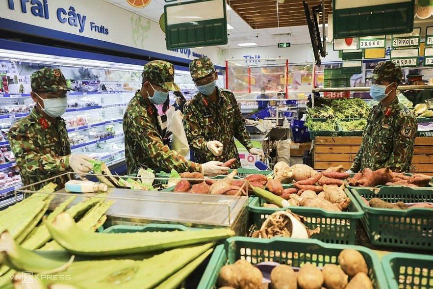 A group of soldiers pick veggies at a supermarket in Binh Thanh District on Wednesday. Photo: VnExpress