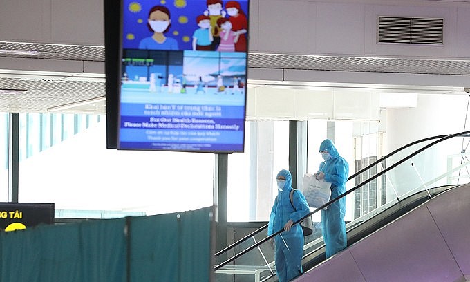 Two passengers wearing protective suits arrive at Hanoi's Noi Bai airport from HCMC, July 2021. Photo: VnExpress