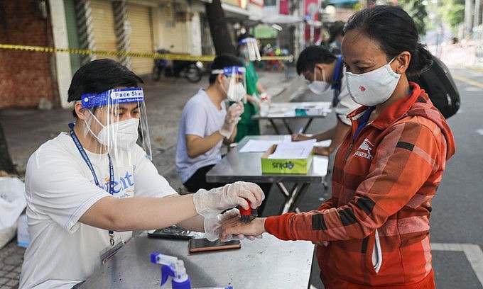 A medical staff stamps ink on the hand of a woman at a shopping location in District 5, Ho Chi Minh City, September 22, 2021. Photo: VnExpress