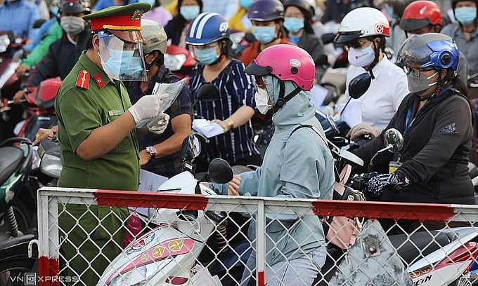 A police officer checks a woman's travel paper at a Covid-19 checkpoint in Go Vap District, HCMC, July 12, 2021. Photo: VnExpress