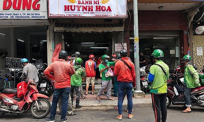 Delivery workers wait for orders at a banh mi restaurant in HCMC's District 1, Oct. 1, 2021. Photo: VnExpress