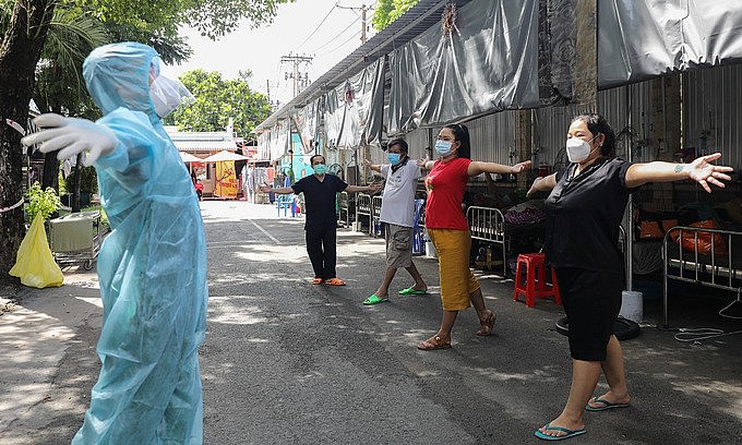 A health worker instructs Covid-19 patients on physicial therapy to restore lung functions in HCMC's District 8, September 21, 2021. Photo: VnExpress