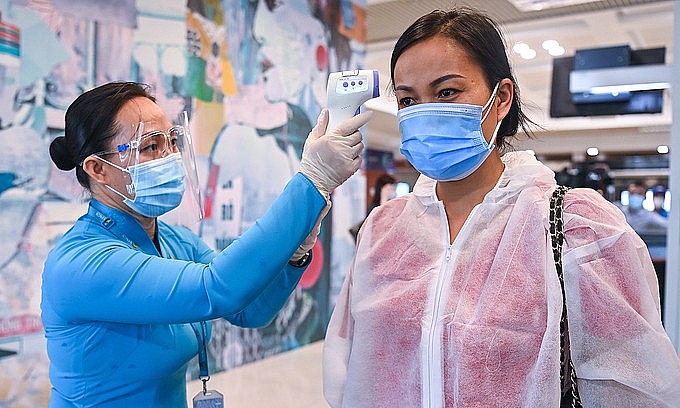A passenger (R) has her body temperature checked at Noi Bai International Airport in Hanoi, October 2021. Photo: VnExpress