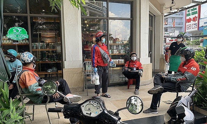 Shippers wait outside a coffee shop for their customers' takeaway drinks in downtown HCMC, October 2021. Photo: VnExpress