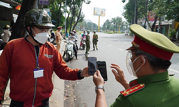 A police officer scans a QR code on a man's phone to see if he violates the social distancing rule in HCMC's Binh Thanh District, August 2021. Photo: VnExpress