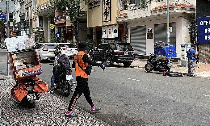 Delivery workers for e-commerce platforms Shopee (orange) and Lazada (blue) wait for customers on Cao Ba Quat Road in HCMC’s District 1, Nov. 16, 2021. Photo: VnExpress