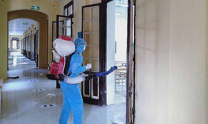 A staff member disinfects a classroom at Hanoi's Phan Dinh Phung High School, preparing for the return of students, Dec. 3, 2021. Photo: VnExpress