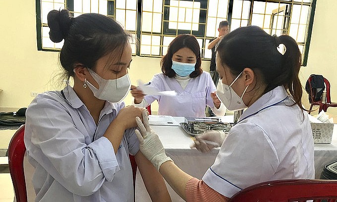 A high school student (L) in Thanh Hoa receives a Covid-19 vaccine shot in December 2021. Photo: VnExpress