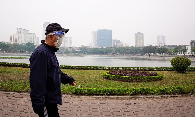 A man wears a face shield outside a mask as he walks by Hanoi's West Lake, December 26, 2021. Photo: VnExpress