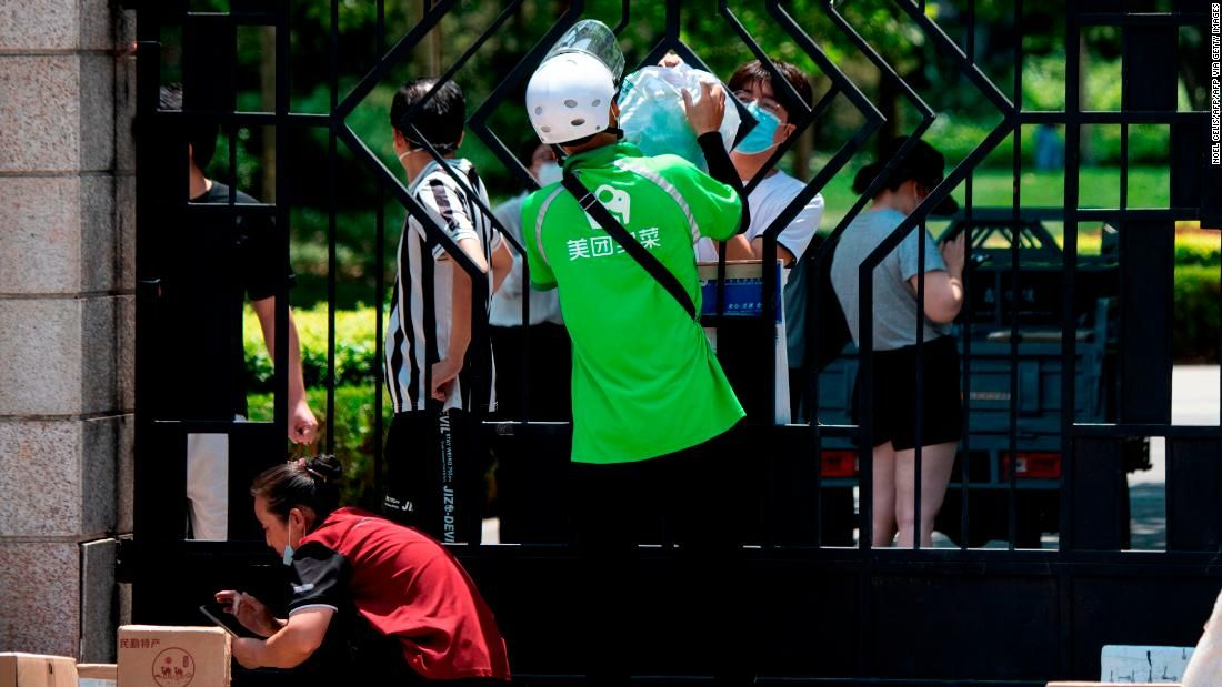 A-delivery-worker-hands-over-items-ordered-online-by-a-resident-living-in-a-compound-under-lockdown-in-Beijing.-Photo:-CNN